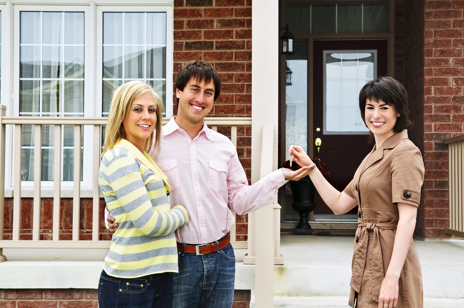 Happy couple getting keys to new house from real estate agent