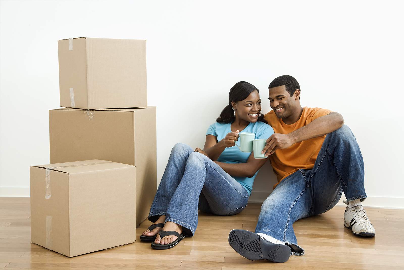 African American male and female couple sitting on floor next to moving boxes relaxing.