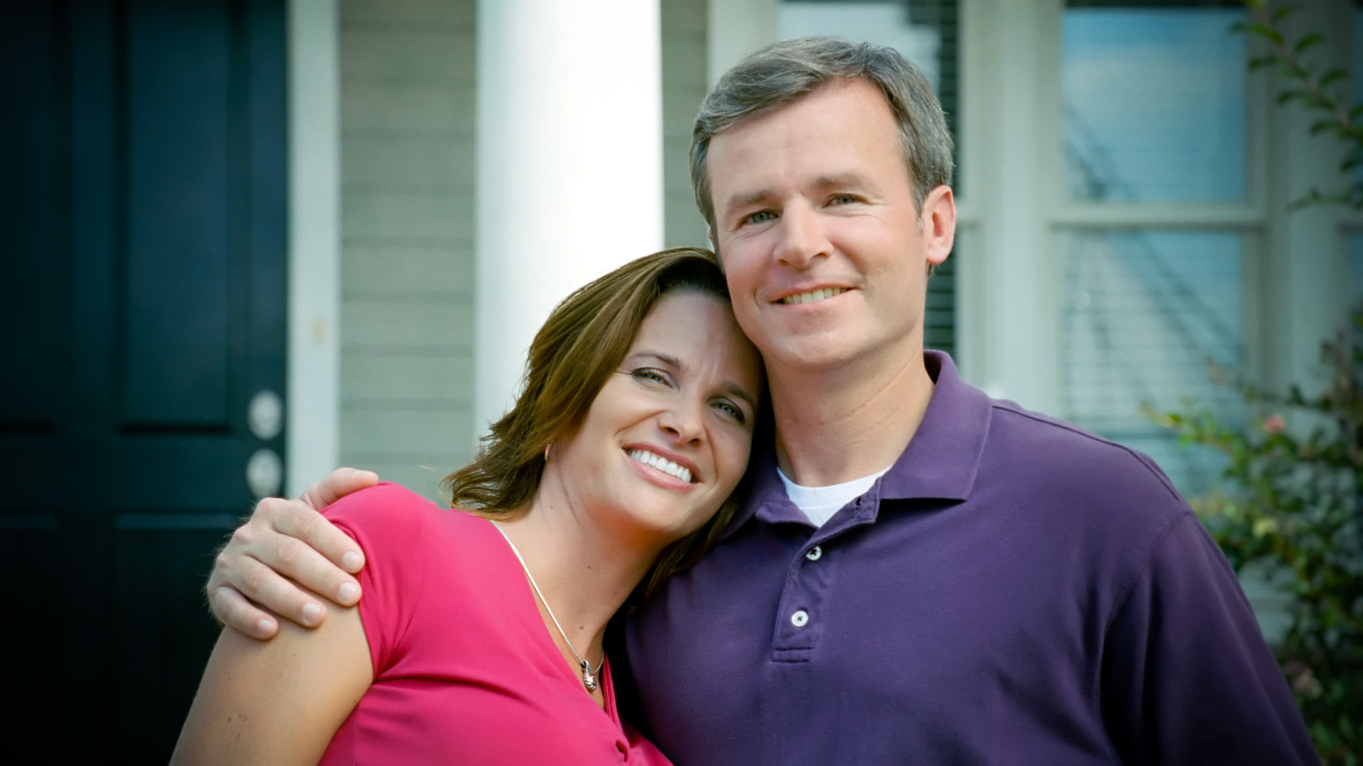 Caucasion Couple Hugs In Front Of New Home