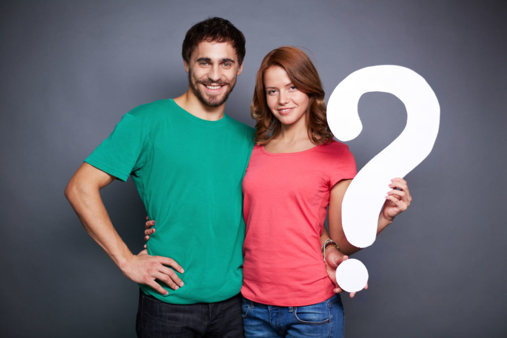 Affectionate couple showing paper question mark and looking at c