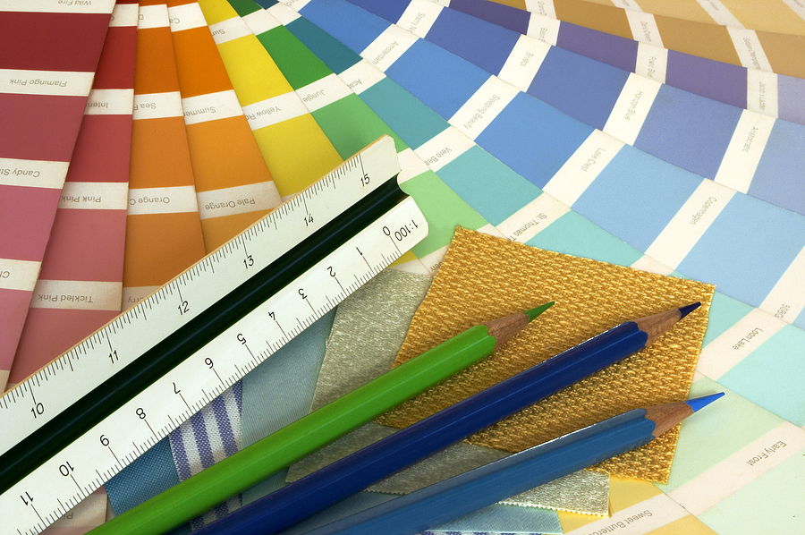 some tools for interior decorating - a paint swatch, fabric samples, colour pencils and a ruler.